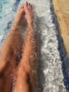 Young womanÃ¢â¬â¢s long tan legs in bright blue pool water